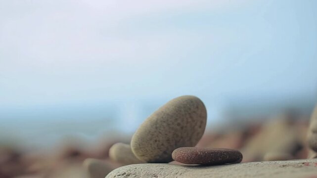 Falling zen stones collapsing on beach shore, smooth pebbles losing balance in slow motion against calm coastal backdrop, symbolic scene of instability and change in nature, meditation concept showing - Powered by Adobe