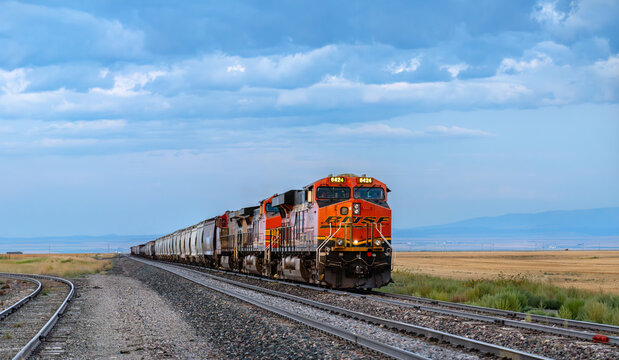 Moccasin, Montana - August 20, 2025: A BNSF freight train, locomotive ET44AC 6424, travels through the rural plains of central Montana under a dramatic cloudy sky
