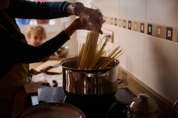 Family Kitchen Pasta: Hands Stirring Long Spaghetti in a Warm Home Setting