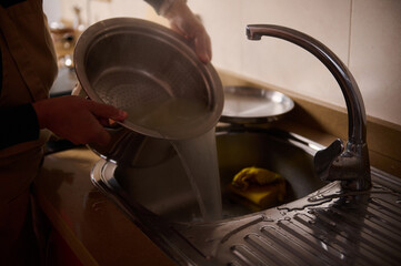 Kitchen Sink Dishwashing Scene With Running Water And Hands Rinsing A Pot