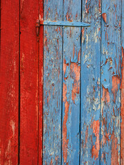 Colorful wooden door with peeling paint in Norway showcasing vibrant red and blue hues in a rustic setting