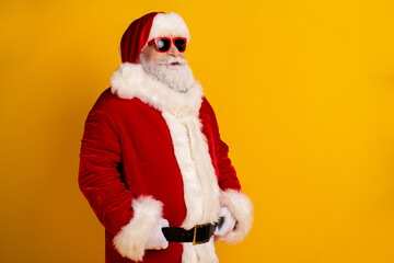 Santa Claus in red suit with white fur coat wearing sunglass posing against yellow background for festive shopping and holiday cheer