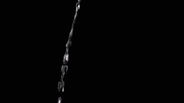 Thin Stream Of Water Pouring On Black Background. Close-up, slow motion. A clear stream of water flows down into empty space. Splashes. Abstract, texture, lighting. Clean water.