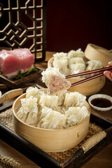 Traditional Chinese Siu Mai Dumplings in Bamboo Steamer with Chopsticks and Soy Sauce