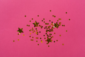 Golden star shape confetti on color background, top view