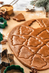 Rolled out pastry dough with cut out Christmas tree shapes on white marble table. Preparation of homemade gingerbread cookies