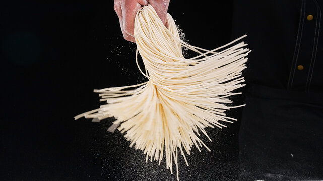 Thin Handrolled Pure Noodles Being Spread with Flour Dust on Dark Surface - Traditional Pasta Making