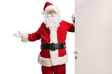 Santa Claus opening a door and gesturing welcome