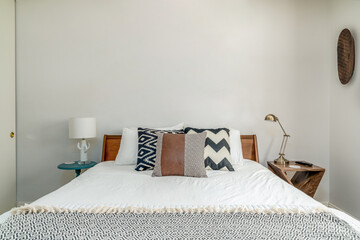 Modern desert bedroom interior. Wood frame bed, accent pillows, lamps.