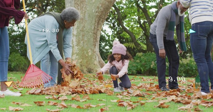 Crouching child in pink jacket and knit hat collecting leaves on grassy lawn, with red rake