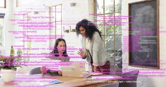 Collaborating women in blazer and dark top leaning over laptop in startup office, with code overlay