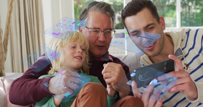 Showing tablet, man tapping holo UI on sofa at home, grandfather wearing glasses and son watching
