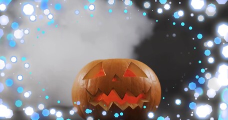 Fototapeta premium Glowing carved pumpkin jack-o'-lantern casting warm studio light, with fog and hexagonal blue bokeh