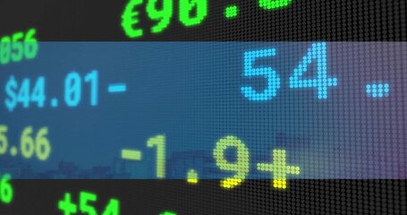 Fototapeta premium Flashing dot-matrix LED ticker showing large colored digits on city facade, with currency signs