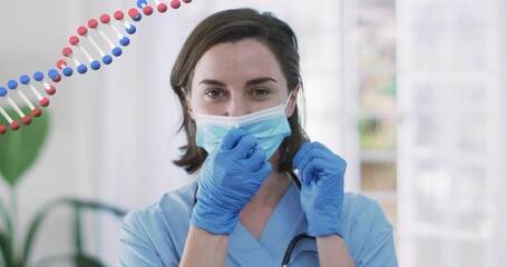 Adjusting clinician securing surgical mask in clinic wearing scrubs gloves stethoscope DNA helix