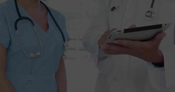 Reading two clinic staff consulting on tablet in clinic, showing stethoscopes lab coat and scrubs - Powered by Adobe