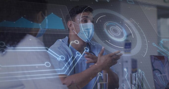 Gesturing male clinician in blue scrubs explaining AR overlay at lab bench with laptop vials masks