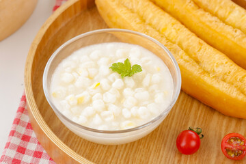 Delicious Fresh Corn Soup with Kernels Garnished with Mint Leaf on Wooden Serving Tray