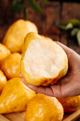 Fresh Asian Pear Slice in Hand - Golden Yellow Fruit with White Flesh on Rustic Wood Background