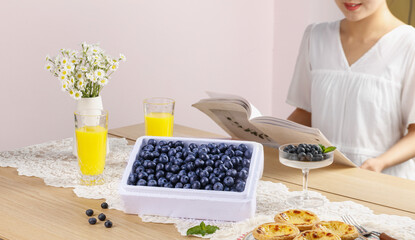 Fresh Blueberries Healthy Breakfast Table Setting with Woman Reading Book and Orange Juice