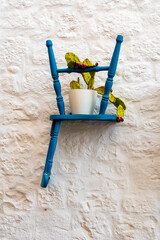 Blue chairs inserted into a wall with potted cacti