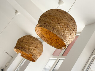 Woven pendant lamps hanging from white ceiling. Natural material, cozy atmosphere, and handmade...