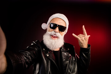 Santa rocker man in leather jacket with white beard wearing black sunglass taking a selfie festive christmas vibe for social media