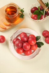 Fresh Red Plums with Herbal Tea - Healthy Food Styling Composition with Vintage Plates and Mint Leaves