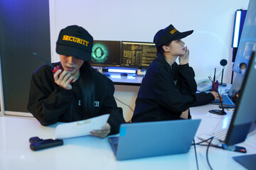 Security officers are checking the TV screen of the CCTV system. 