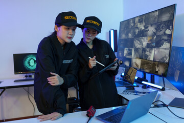 Security officers are checking the TV screen of the CCTV system. 