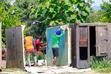 Construction Workers Dismantling and Recycling Old Container Panels Outdoors