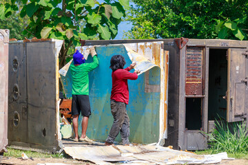 Construction Workers Dismantling and Recycling Old Container Panels Outdoors