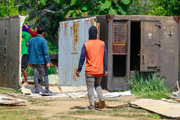 Construction Workers Dismantling and Recycling Old Container Panels Outdoors