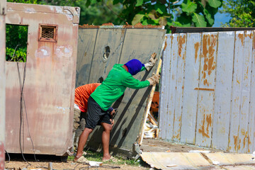 Construction Workers Dismantling and Recycling Old Container Panels Outdoors