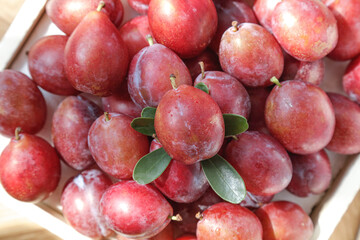 Fresh Red Plums in Wooden Basket with Green Leaves - Ripe Stone Fruit Display