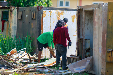 Construction Workers Dismantling and Recycling Old Container Panels Outdoors