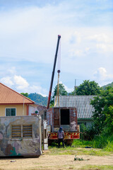 Mobile Crane Lifting Rusty Container onto Truck in Residential Area