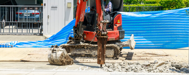 Small Mini Excavator with Hydraulic Breaker Jackhammer Drilling Concrete on Construction Site