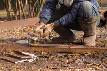 A construction worker working with a grinder outdoors on steel structures