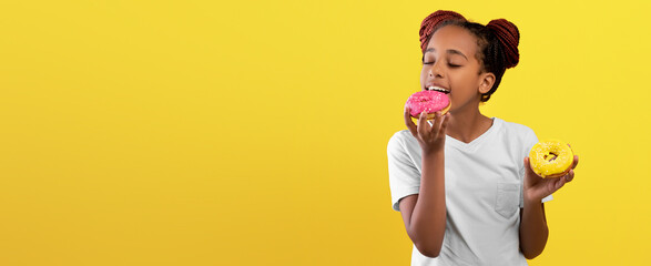 A girl with braided hair happily holds two donuts, one pink and one yellow, with a joyful...