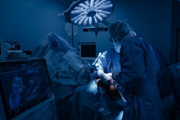 In a brightly lit operating room, surgeons use robotic technology during a knee replacement. A screen displays planning data, assisting with precision and personalized alignment