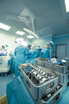 Inside a brightly lit operating room, surgical personnel in blue scrubs prepare for a robotic-assisted knee replacement using advanced medical instruments and the robotic surgical knee system