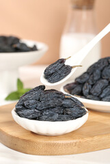 Black Dried Grapes from Xinjiang Turpan in White Bowls on Wooden Board