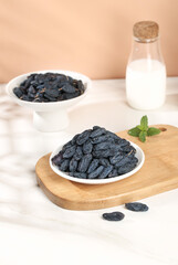 Dried Black Grapes from Xinjiang Turpan China in White Bowls with Milk Bottle on Wooden Cutting Board