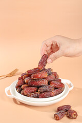 Hand Picking Fresh Dried Dates from Bowl - Healthy Middle Eastern Food Concept