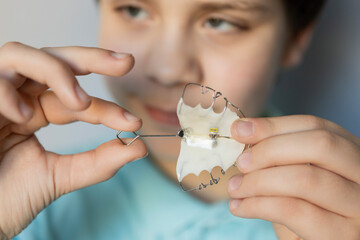 Young boy holding a dental appliance to correct teeth alignment at home