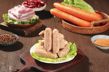 Raw sausages and meat ingredients with vegetables on wooden table ready for barbecue grilling preparation