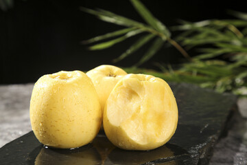Fresh Yellow Cored Apples Sweet Crunchy Fruit Variety on Dark Slate Surface with Palm Leaves Background
