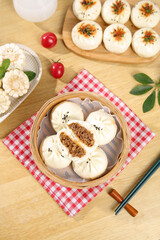 Delicious Asian steamed beef buns in bamboo basket - traditional breakfast meal with chopsticks on wooden table