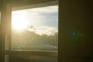 Sunlight streaming through dusty window glass in warm golden morning atmosphere